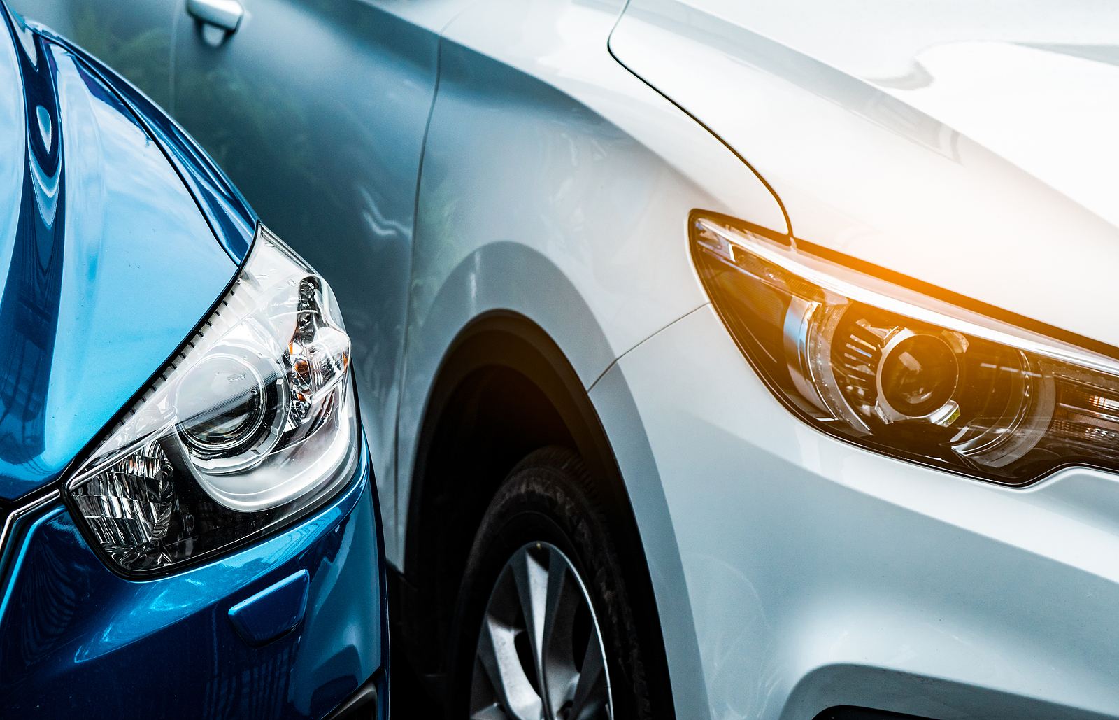 Close up headlamp light of blue and white SUV car. Blue car parked beside white car. Automotive industry concept. Electric or hybrid auto concept. Car service. Road trip adventure. Automobile rental.